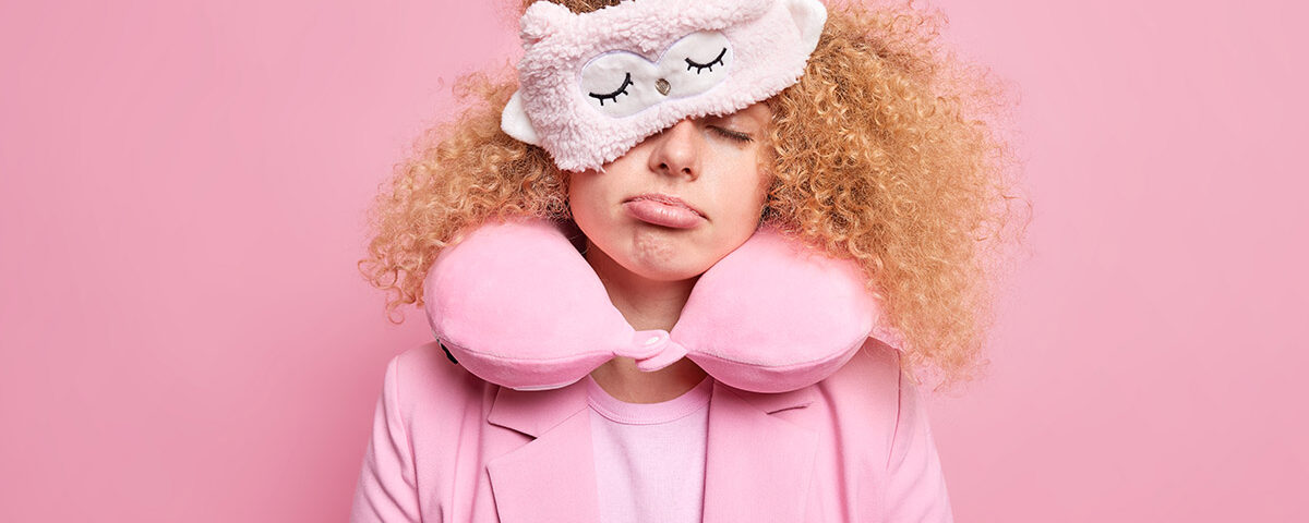 Κοπέλα με ροζ μπουρνούζι και μάσκα ύπνου κουρασμένη.