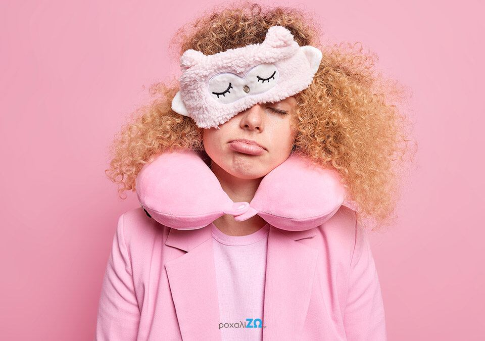 Κοπέλα με ροζ μπουρνούζι και μάσκα ύπνου κουρασμένη.