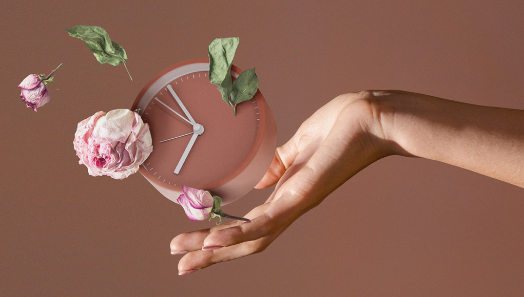 Ένα γυναικείο χέρι κρατάει ένα ρολόι και ρίχνει λουλούδια.