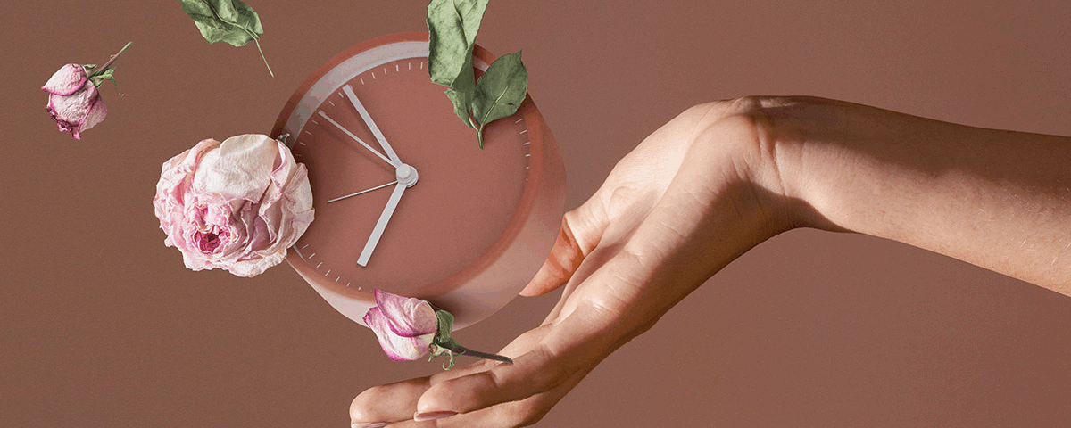 Ένα γυναικείο χέρι κρατάει ένα ρολόι και ρίχνει λουλούδια.