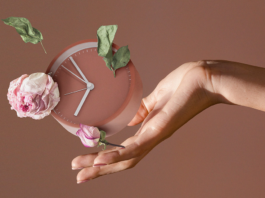 Ένα γυναικείο χέρι κρατάει ένα ρολόι και ρίχνει λουλούδια.